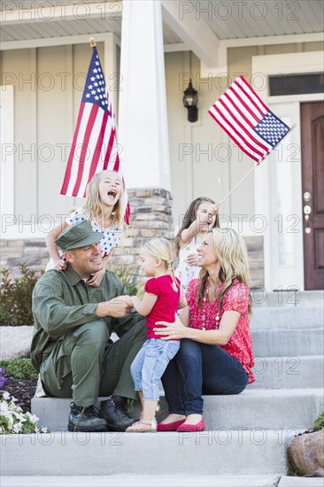 Caucasian soldier and family playing together on front stoop