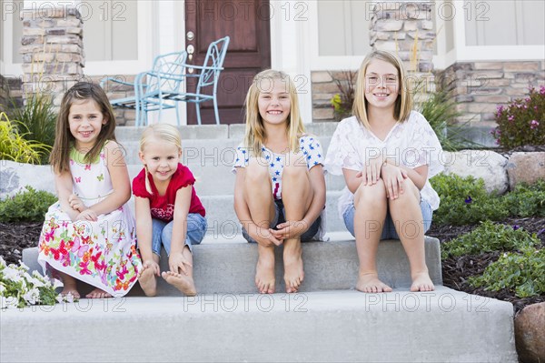 Caucasian sisters smiling on front stoop