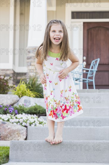 Laughing Caucasian girl standing on front stoop