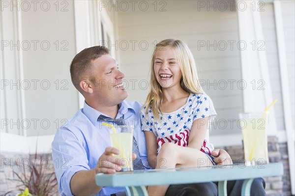 Caucasian father and daughter laughing on porch