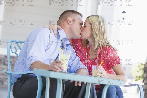 Caucasian couple kissing on porch