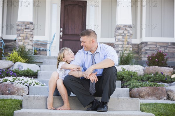 Caucasian father and daughter sitting on front stoop