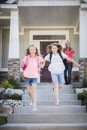 Caucasian mother sending running sisters to school