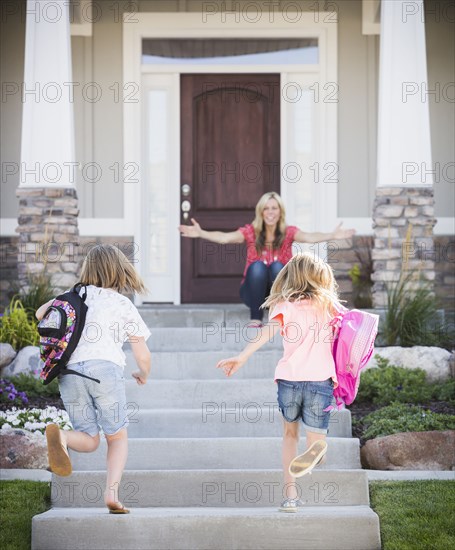 Caucasian mother greeting daughters returning home from school