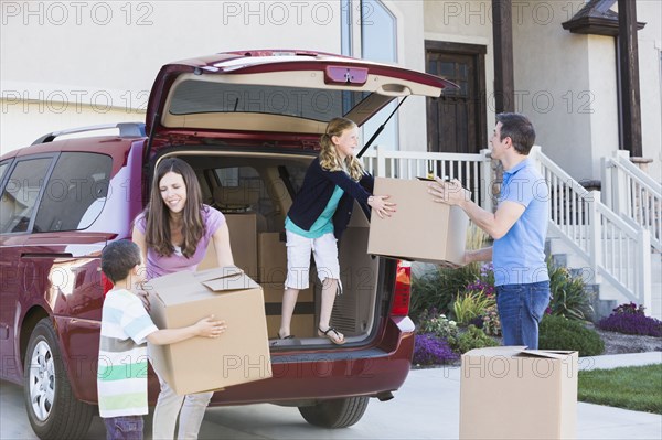 Caucasian family unpacking cardboard boxes from car