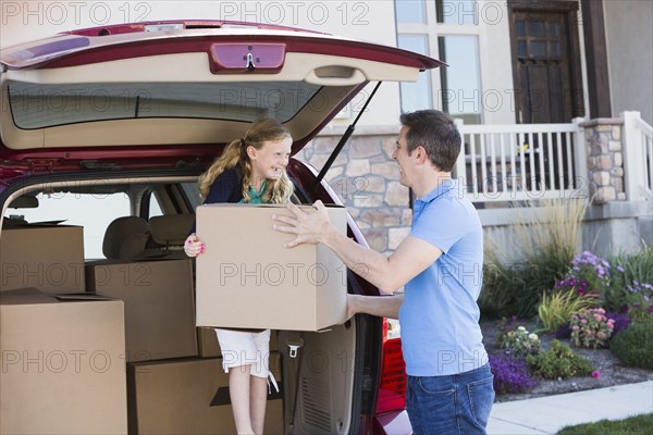 Caucasian family unpacking cardboard boxes from car