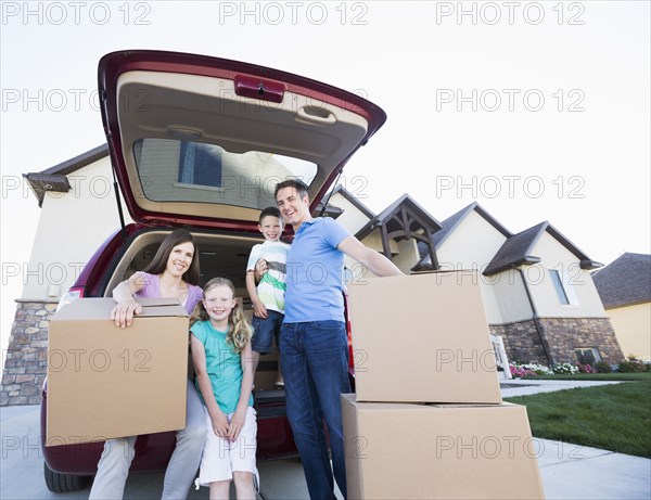 Caucasian family unpacking cardboard boxes from car