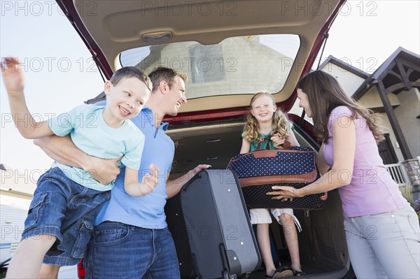 Caucasian family unpacking suitcases from car