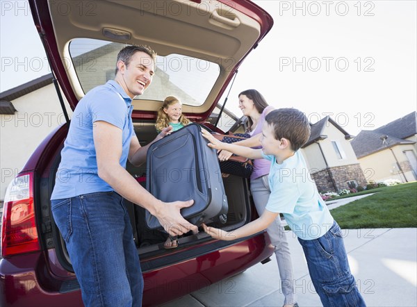 Caucasian family unpacking suitcases from car