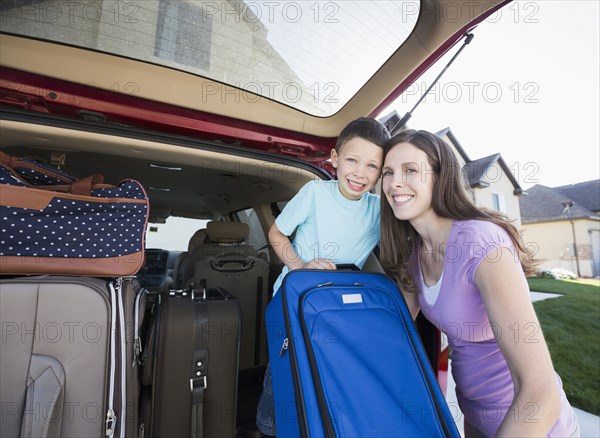 Caucasian mother and son smiling with suitcases in car