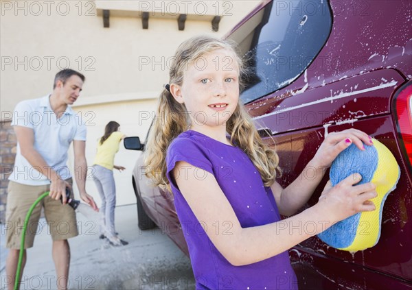 Caucasian father and children washing car in driveway