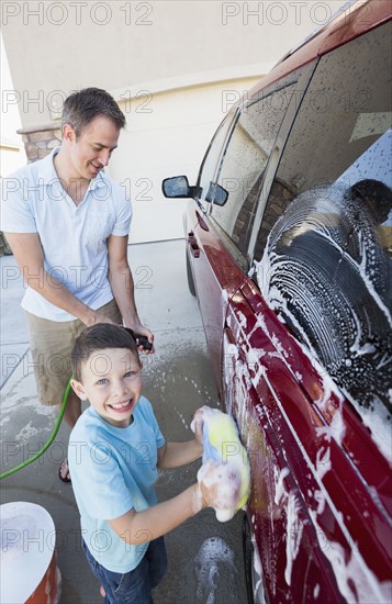 Caucasian father and son washing car in driveway