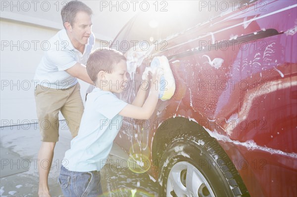 Caucasian father and son washing car in driveway