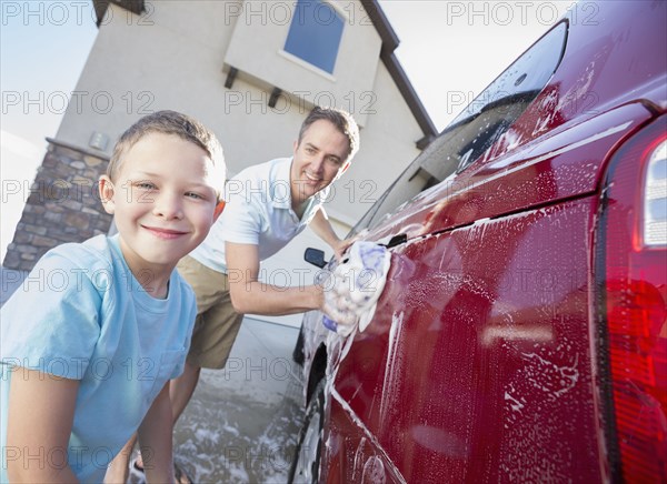 Caucasian father and son washing car in driveway