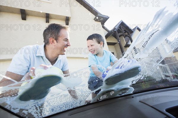 Caucasian father and son washing car windshield