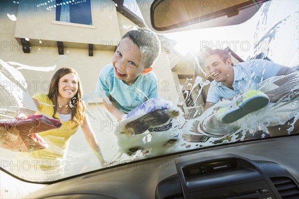 Caucasian father and children washing car windshield
