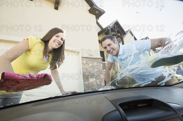 Caucasian couple washing car windshield