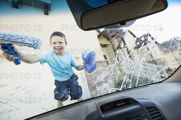 Caucasian boy washing car windshield