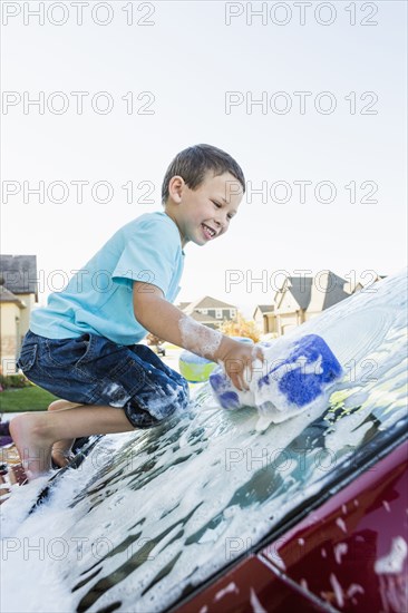 Caucasian boy washing car windshield