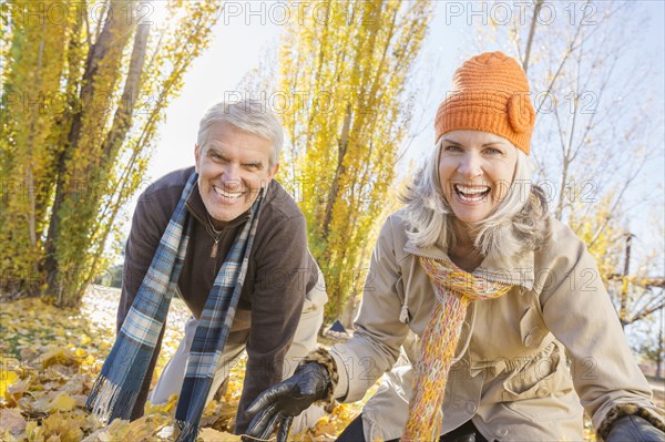 Older Caucasian couple playing in autumn leaves