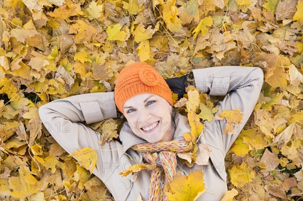 Older Caucasian woman smiling in autumn leaves