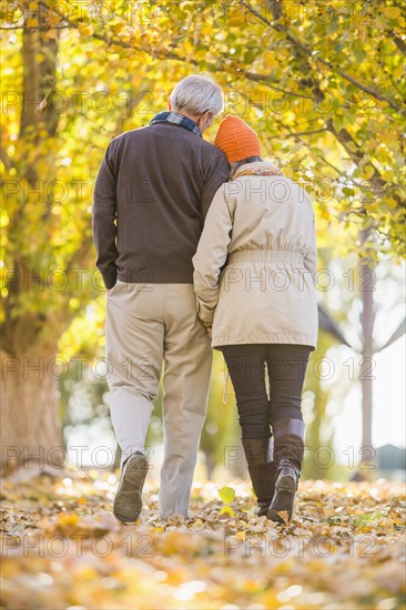 Older Caucasian couple walking under autumn trees