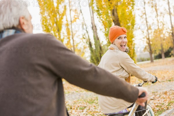 Older Caucasian couple riding bicycles on autumn leaves