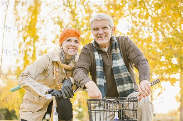 Older Caucasian couple riding bicycles near autumn trees