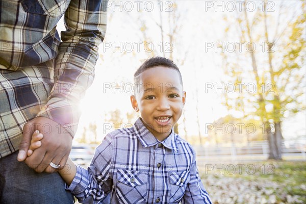Black father and son walking in autumn leaves