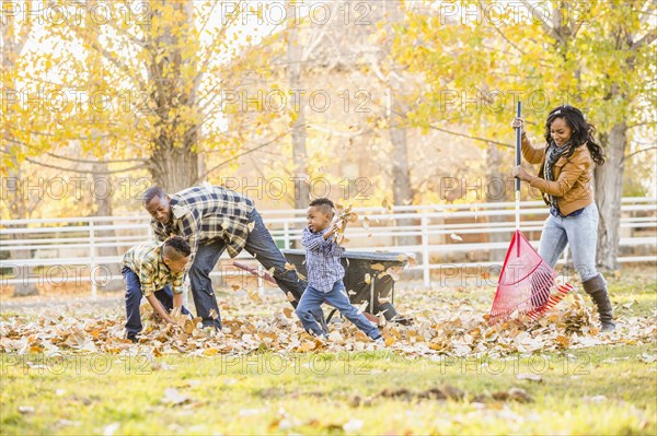 Family raking autumn leaves together