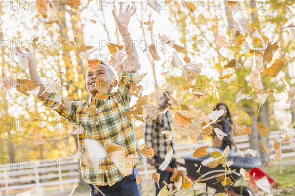 Boy playing in autumn leaves