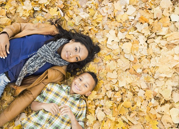 Mother and son laying together in autumn leaves