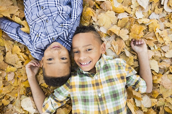 Brothers laying together in autumn leaves