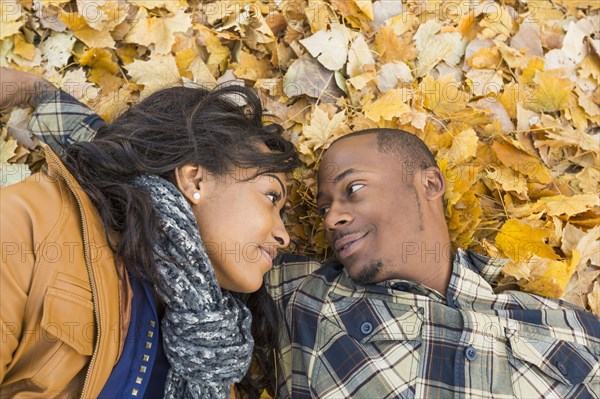 Black couple laying together in autumn leaves