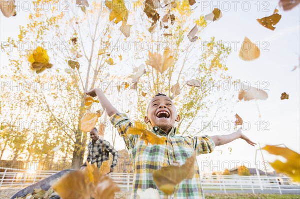 Boy playing in autumn leaves