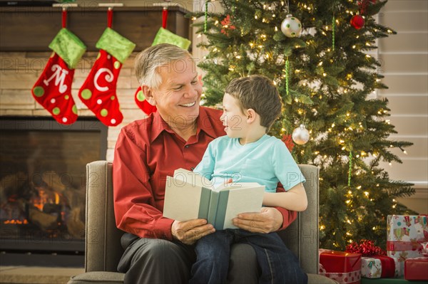 Caucasian grandfather reading to grandson at Christmas