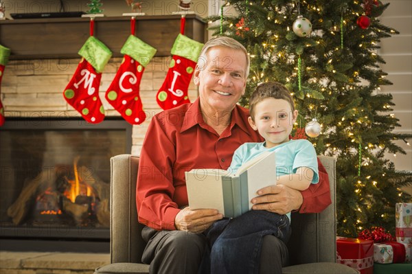 Caucasian grandfather reading to grandson at Christmas