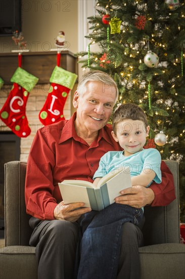 Caucasian grandfather reading to grandson at Christmas