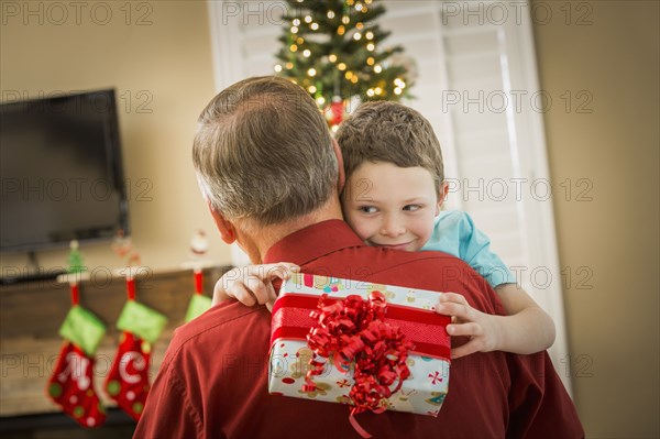 Caucasian grandson hugging grandfather with Christmas gift