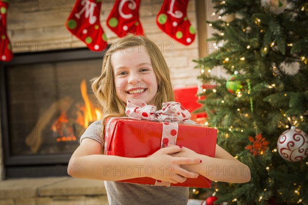 Caucasian girl hugging Christmas gift