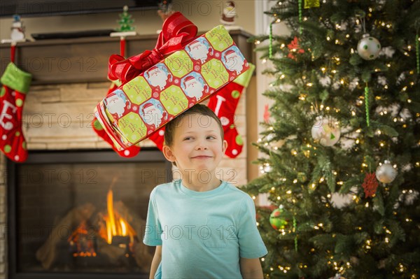 Caucasian boy balancing Christmas gift on head