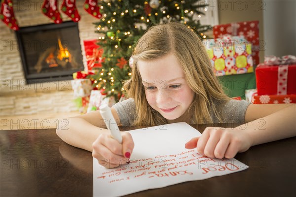 Caucasian girl writing to Santa at Christmas