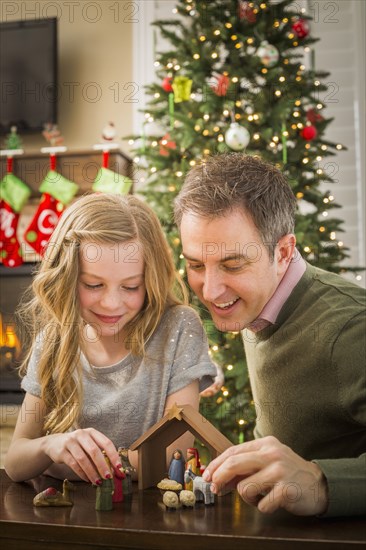 Caucasian father and daughter arranging nativity at Christmas