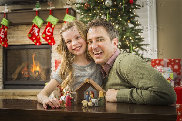 Caucasian father and daughter arranging nativity at Christmas