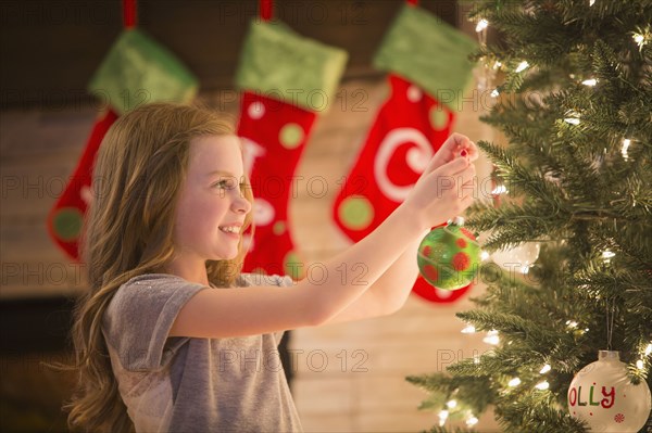 Caucasian girl decorating Christmas tree