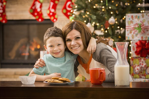 Caucasian mother and son leaving cookies and milk for Santa at Christmas