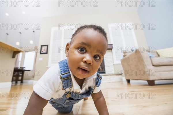 Black baby crawling on living room floor