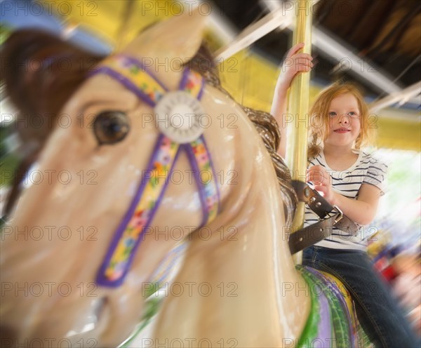 Caucasian girl riding horse on carousel