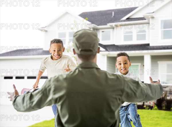 Returning soldier greeting children outside house
