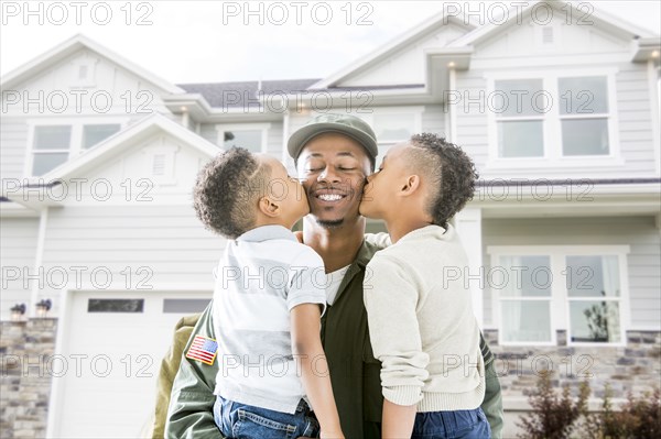 Boys kissing cheeks of soldier father